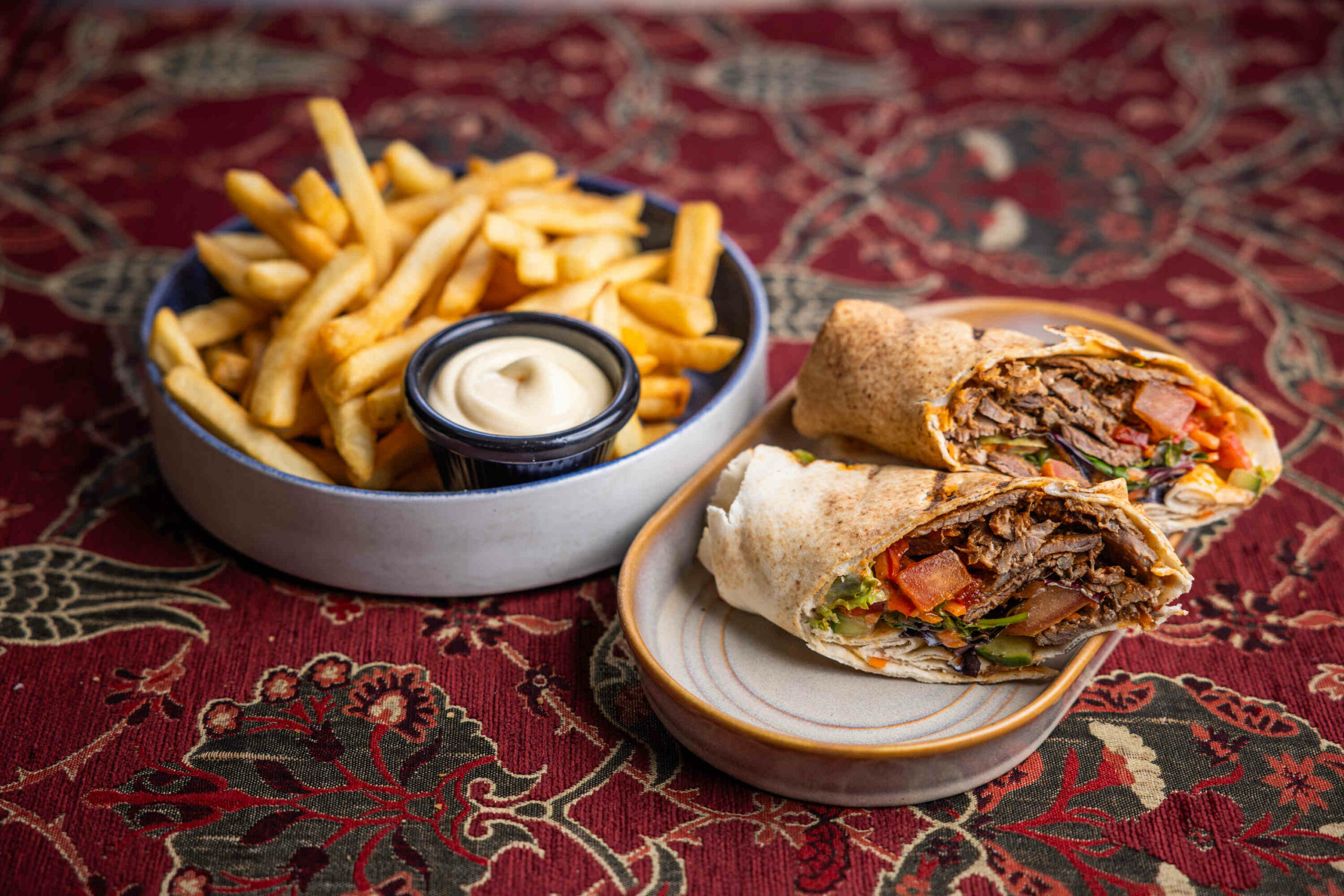 Photo of a lamb shish Turkish Lunch Wrap with a side of chips and aioli.
